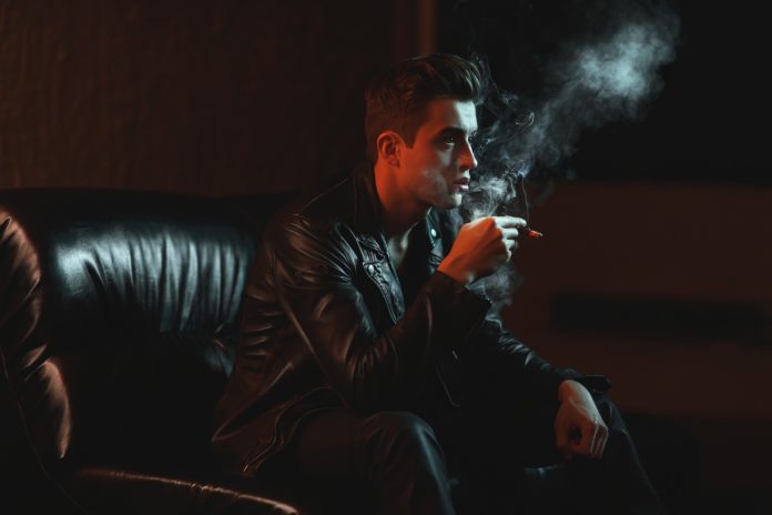 Chico fumando en un sofá